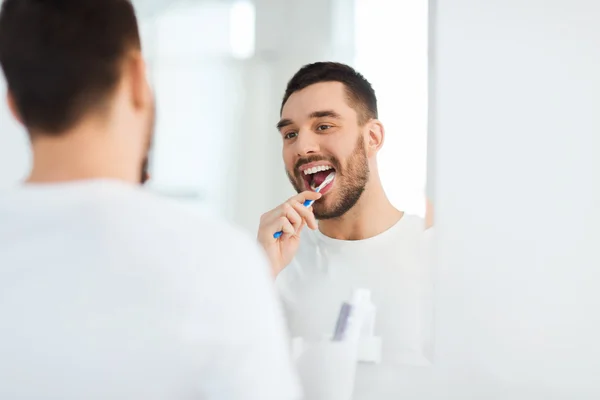 Man met tandenborstel reiniging van de tanden in de badkamer — Stockfoto