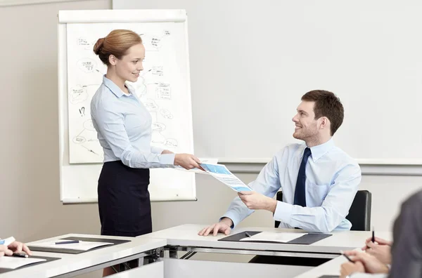 Smiling woman giving papers to man in office — Stock Photo, Image