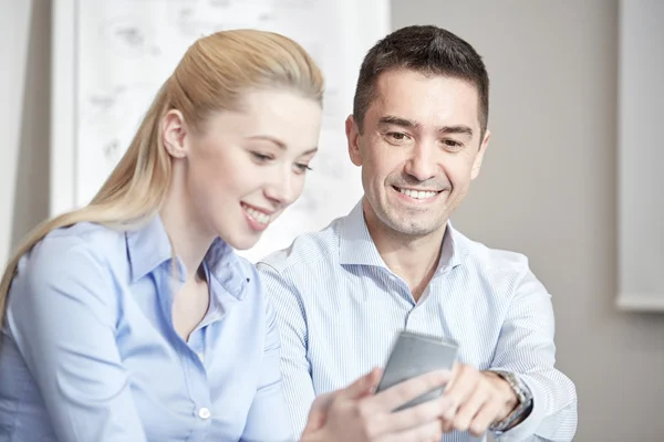 Empresários sorridentes com smartphones no escritório — Fotografia de Stock