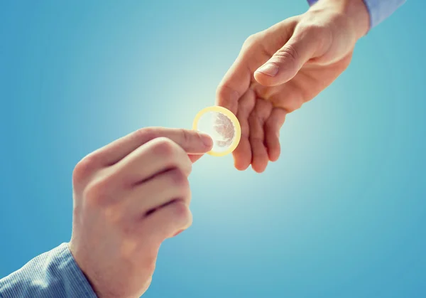 Close up of male gay couple hands giving condom — Stock Photo, Image