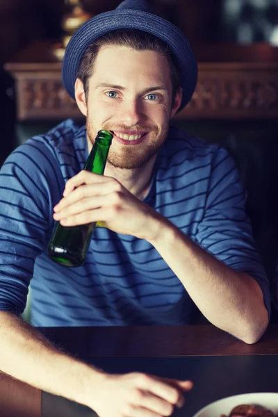 Jovem feliz bebendo cerveja no bar ou pub — Fotografia de Stock