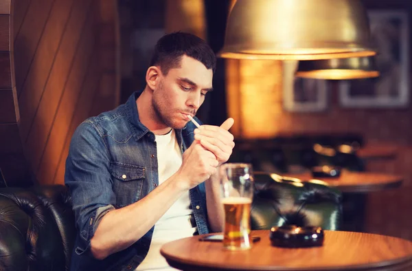 Man drinking beer and smoking cigarette at bar — Stock Photo, Image