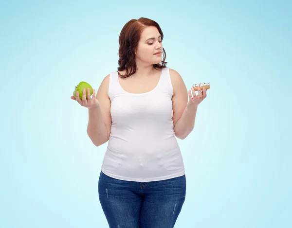 Νέοι συν μέγεθος γυναίκα επιλέγοντας μήλο ή cookie — Φωτογραφία Αρχείου
