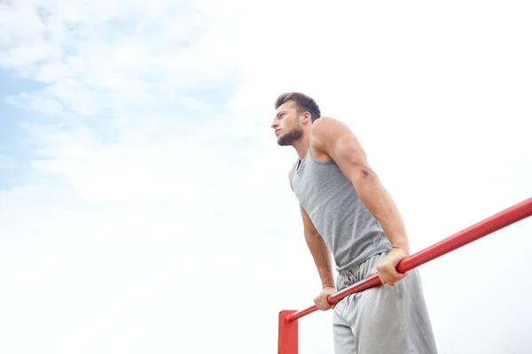 Joven ejercitándose en barra horizontal al aire libre — Foto de Stock