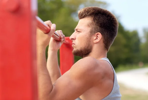 Jongeman die buiten op de horizontale balk traint — Stockfoto