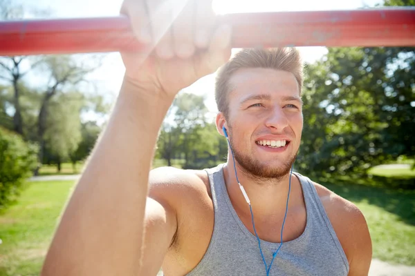 Glücklicher junger Mann mit Kopfhörern und horizontaler Stange — Stockfoto