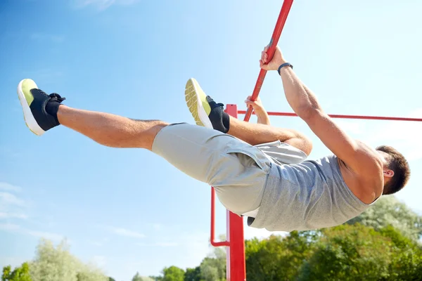 young man exercising on horizontal bar outdoors