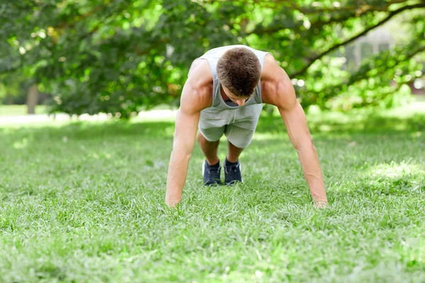 Joven haciendo flexiones en la hierba en el parque de verano —  Fotos de Stock