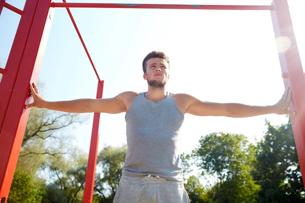 Young man exercising on horizontal bar outdoors — Stock Photo, Image