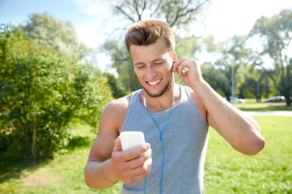 Homme heureux avec écouteurs et smartphone au parc — Photo