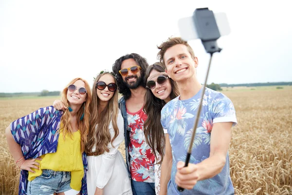 Amigos hippies con smartphone en palo selfie — Foto de Stock