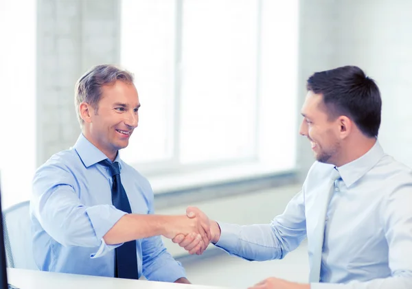 Businessmen shaking hands in office — Stock Photo, Image