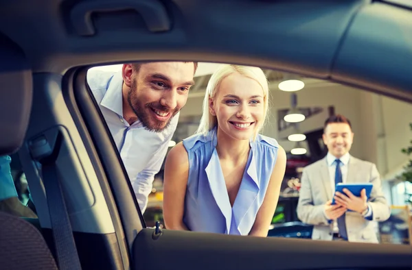 Šťastný pár s prodejci aut v autosalonu nebo salónek — Stock fotografie
