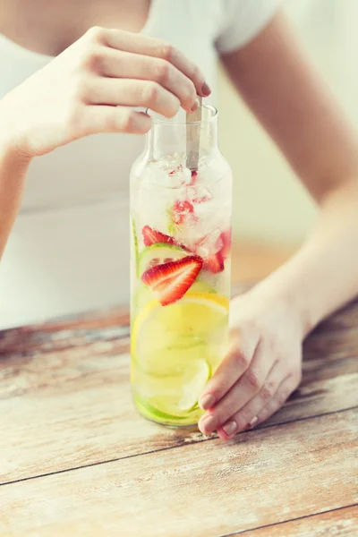 Close up of woman with fruit water in glass bottle — Stock Photo, Image