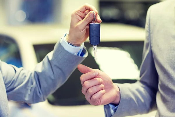 Primer plano de manos masculinas con la llave del coche en salón auto —  Fotos de Stock