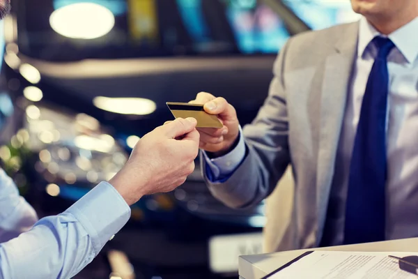 Customer giving credit card to car dealer in salon — Stock Photo, Image