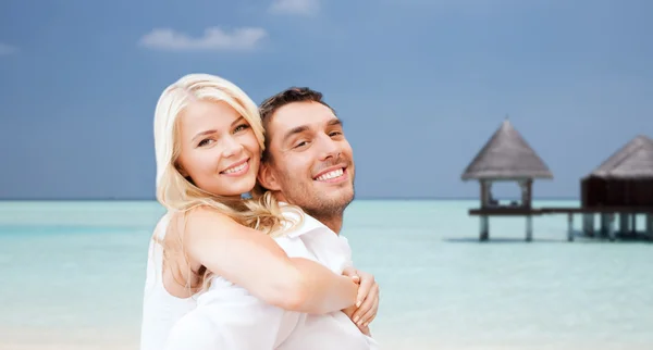 Casal feliz se divertindo na praia com bungalow — Fotografia de Stock