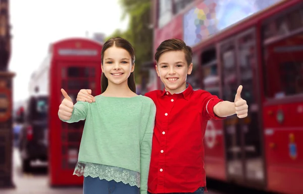 Niños felices mostrando pulgares hacia arriba sobre la ciudad de Londres — Foto de Stock