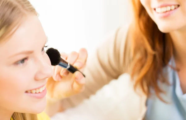 Mujeres felices con cepillo de maquillaje aplicando rubor —  Fotos de Stock