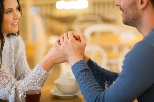 Happy couple with tea holding hands at restaurant — Stock Photo, Image