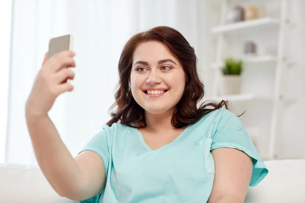Glada plus size kvinna med smartphone hemma — Stockfoto