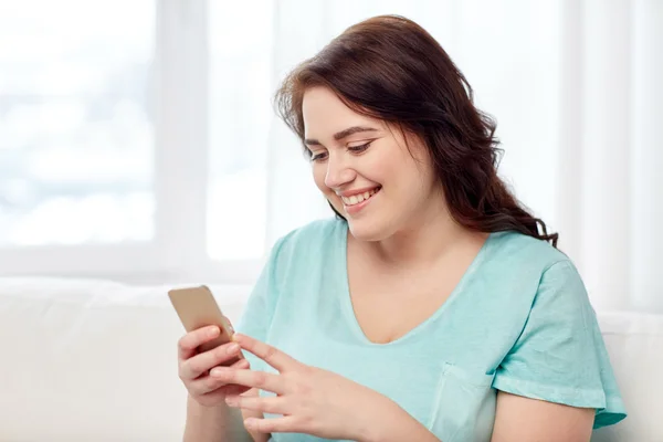 Gelukkig plus size vrouw met smartphone thuis — Stockfoto