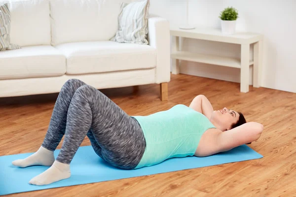 Además de la mujer de tamaño haciendo ejercicio en la estera en casa — Foto de Stock