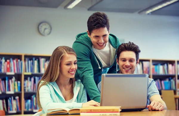 Zadowoleni uczniowie z laptopa w bibliotece — Zdjęcie stockowe