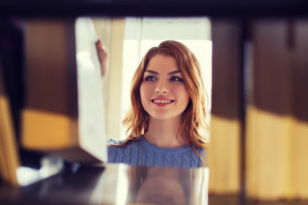 Felice studentessa o donna con libro in biblioteca — Foto Stock