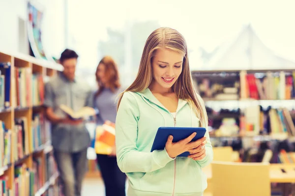 Heureuse étudiante fille avec tablette PC dans la bibliothèque — Photo