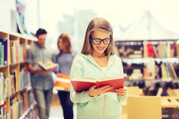 Menina estudante feliz ou mulher com livro na biblioteca — Fotografia de Stock