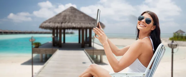 Mulher sorridente com tablet pc banhos de sol na praia — Fotografia de Stock