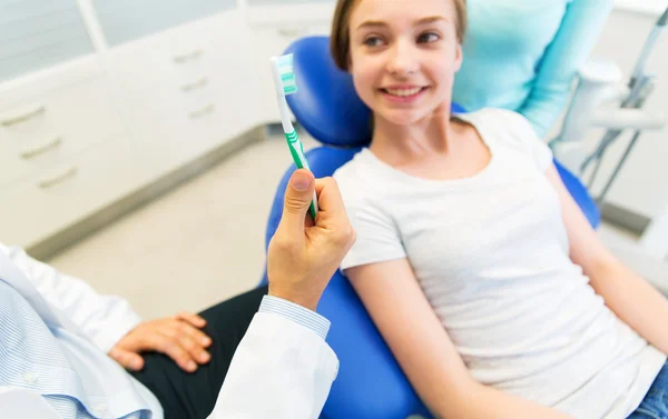 Primer plano de la mano del dentista con cepillo de dientes y niña — Foto de Stock