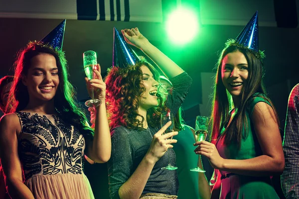 Улыбающиеся друзья с бокалами шампанского в клубе Стоковое Фото