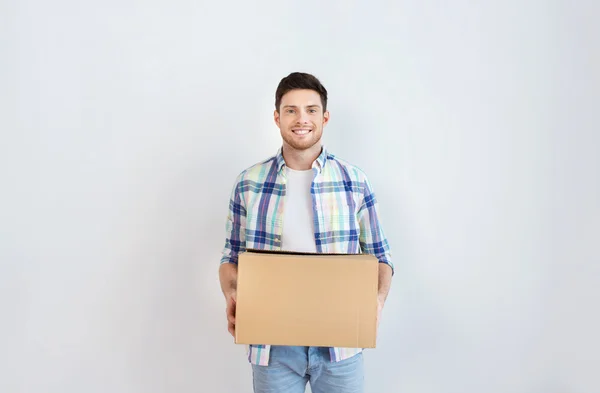 Smiling young man with cardboard box at home — Stock Photo, Image