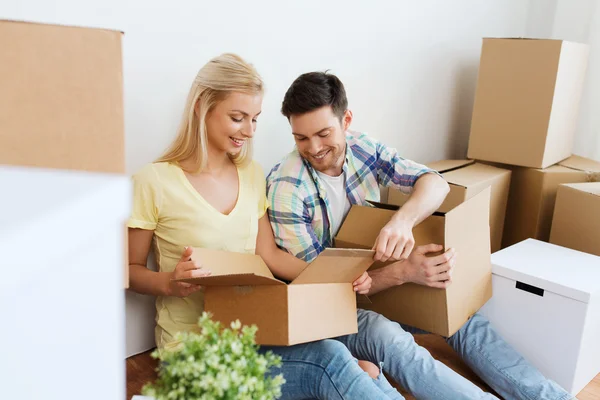 Sonriente pareja con muchas cajas mudándose a un nuevo hogar — Foto de Stock