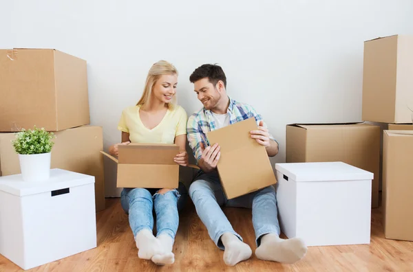 Sonriente pareja con muchas cajas mudándose a un nuevo hogar — Foto de Stock