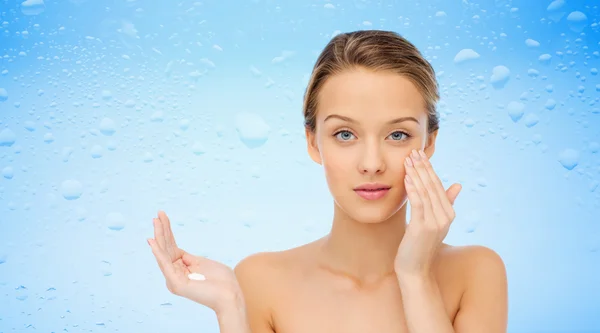 Mujer joven aplicando crema en su cara — Foto de Stock