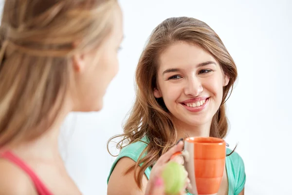 Glückliche junge Frauen, die zu Hause Tee mit Süßigkeiten trinken — Stockfoto