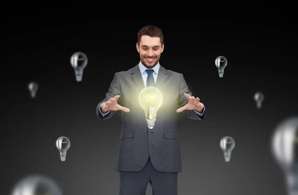 Homem de negócios trabalhando com ícones de lâmpada — Fotografia de Stock