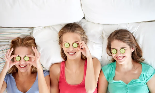 Gelukkig jonge vrouwen met komkommer masker liggend in bed — Stockfoto
