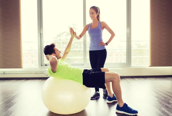 Homme et femme souriants avec ballon d'exercice dans la salle de gym — Photo