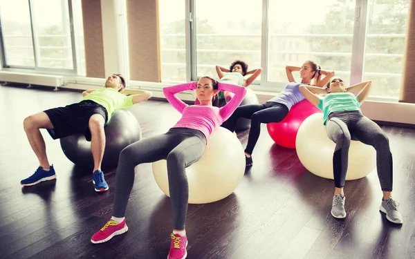 Personas felices flexionando los músculos abdominales en el fitball —  Fotos de Stock