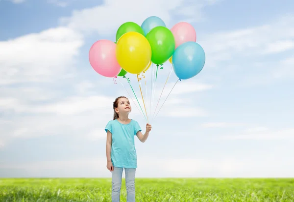 Chica mirando hacia arriba con montón de globos de helio — Foto de Stock