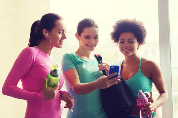 Szczęśliwe kobiety z butelki i smartphone w siłowni — Zdjęcie stockowe
