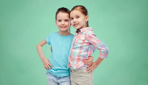 Lächelnde Mädchen umarmen grüne Schultafel — Stockfoto