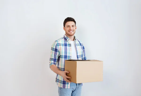 Sonriente joven con caja de cartón en casa — Foto de Stock