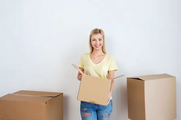 Giovane donna sorridente con scatola di cartone a casa — Foto Stock