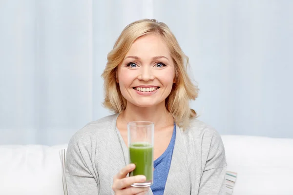 Ευτυχισμένη γυναίκα πίνοντας πράσινο χυμό ή ανακινείται στο σπίτι — Φωτογραφία Αρχείου