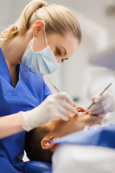 Dentista feminino verificando dentes de paciente do sexo masculino — Fotografia de Stock